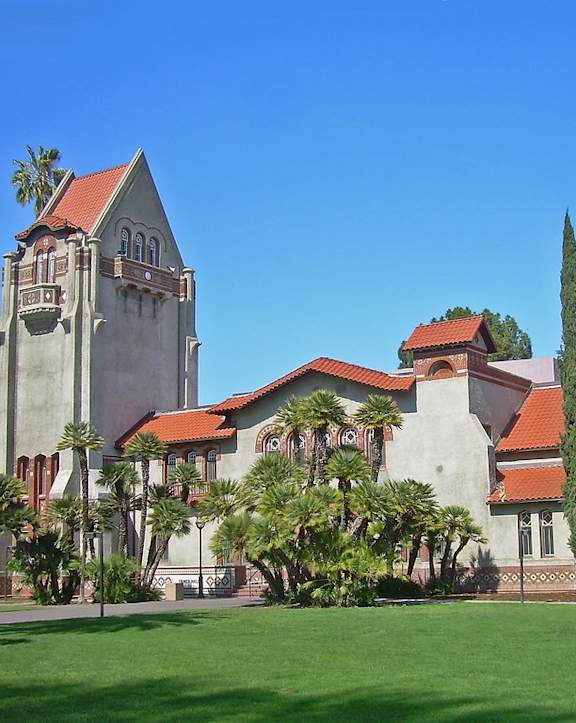 a church with a clock tower and a green lawn