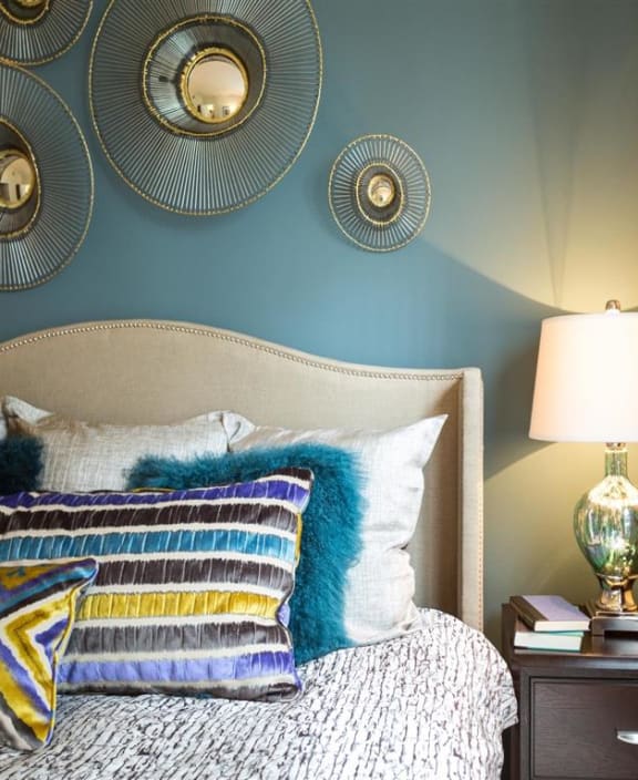 a bedroom with blue walls and a bed with pillows and a lamp at The Arbor Walk Apartments, Florida