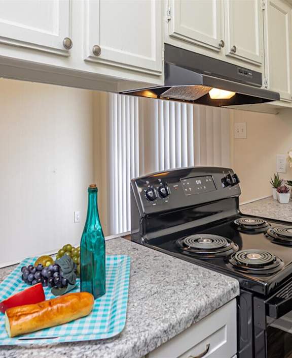 a kitchen counter wih a tray of fruit and a black stove