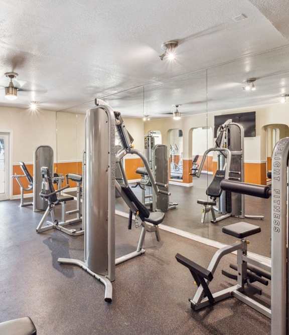 A gym with a variety of equipment including treadmills, weights, and exercise machines.