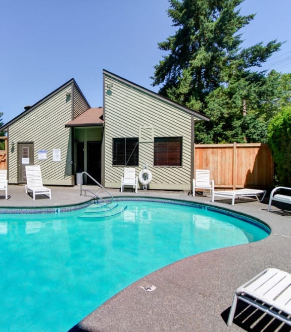 a swimming pool in front of a house with a pool and chairs