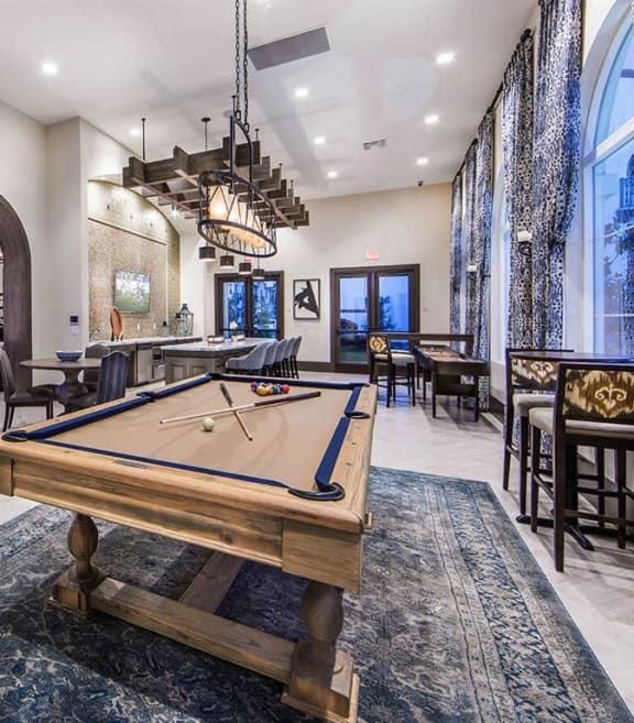 a pool table in a clubhouse with a bar and tables