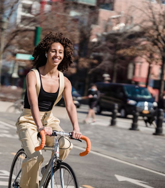A woman with curly hair is riding a blue bicycle on a city street.