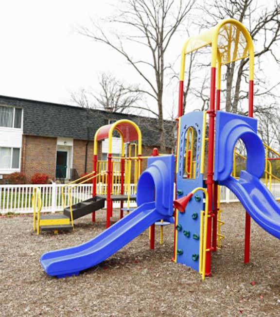 A playground with a blue slide and yellow and red structures.