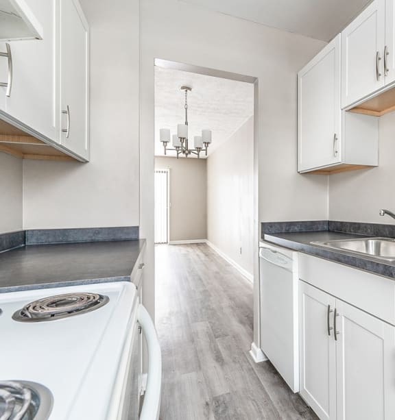 a kitchen with white cabinets and a white stove and sink