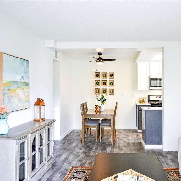 A living room and kitchen with a table and a ceiling fan and a couch at Hillside Village. 