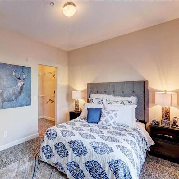 A large/cozy bedroom with a queen-size bed, a dresser, decorations, closet, and nightstands at Residence at North Penn Apartment Homes. 
