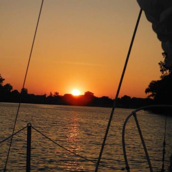 a sunset over a body of water with trees in the background