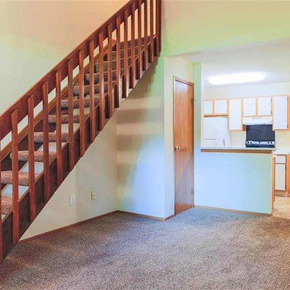 A room with a staircase and a door leading to another room.