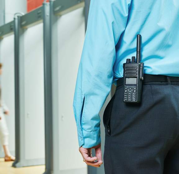 A security guard is talking on a walkie-talkie.