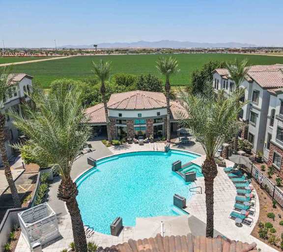 A swimming pool surrounded by palm trees and apartment buildings.