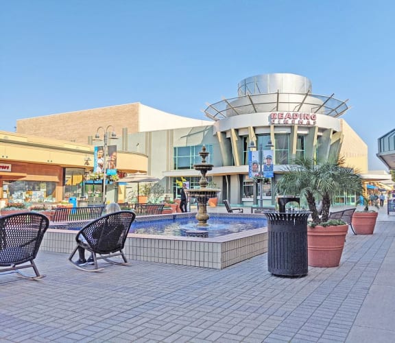 a fountain outside of a shopping mall with a building in the background