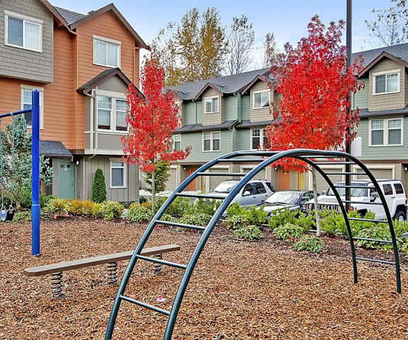 Kenmore WA Apartments - Northshore Townhomes - Outdoor Playground with Metal Bars, Swings, and Surrounding Trees