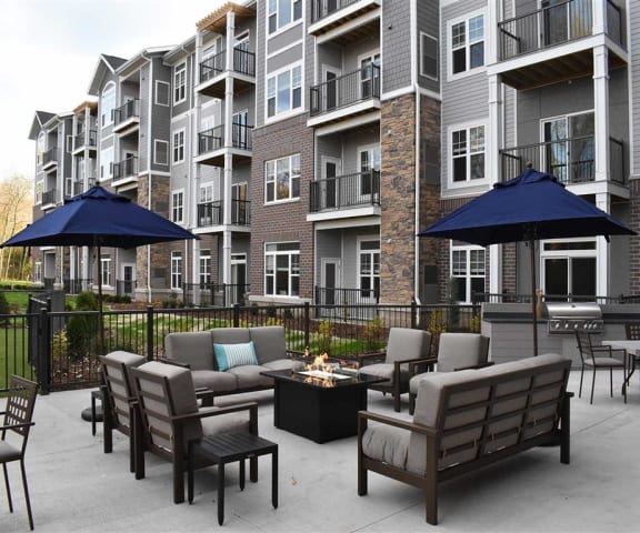 an outdoor patio with furniture and a grassy area in front of an apartment building