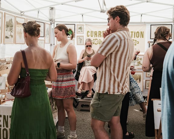 A group of people are standing under a tent with a sign that says "CORRUPTION".