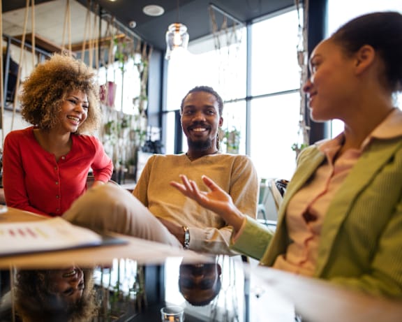 Three people are sitting around a table, having a conversation.