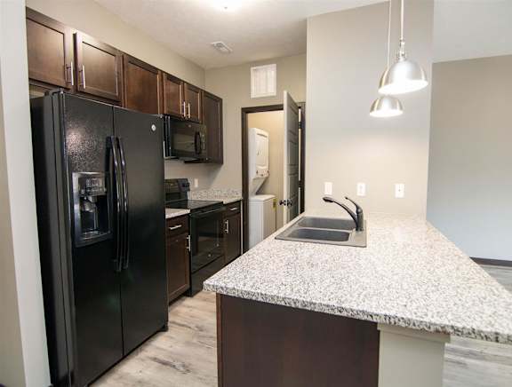 Gallery style kitchen with dark brown cabinets and black appliances