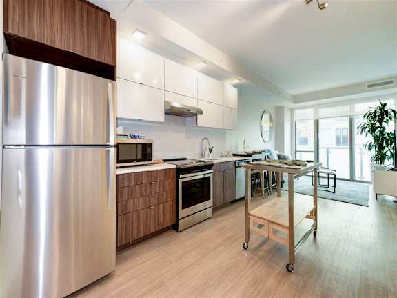 A modern kitchen with a stainless steel refrigerator and wooden cabinets.