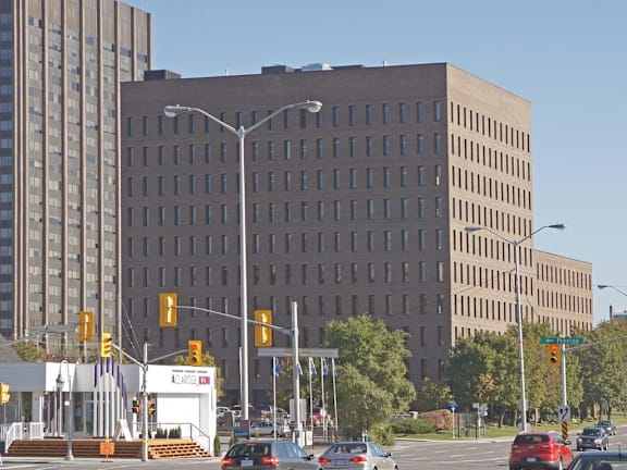 A large building with a lot of windows is in the background of a busy street.