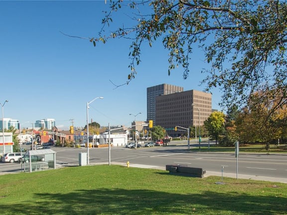 A city street with a large building in the background and a grassy area in the foreground.