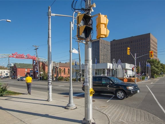 A pedestrian is walking on a sidewalk next to a traffic light.
