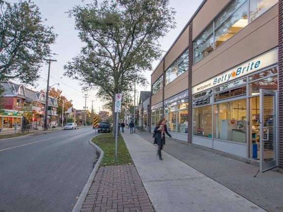 A woman is walking down a sidewalk past a Belty Brite store.