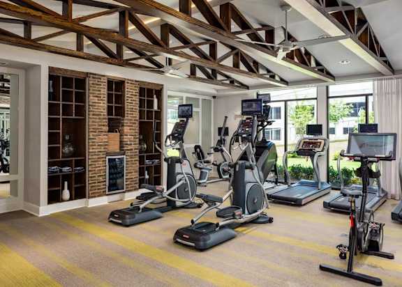 A gym with a variety of exercise equipment including treadmills, stationary bikes, and elliptical machines.