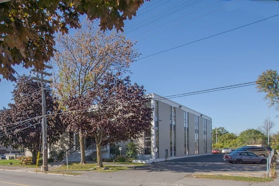 A street view with a building on the right and trees on the left.
