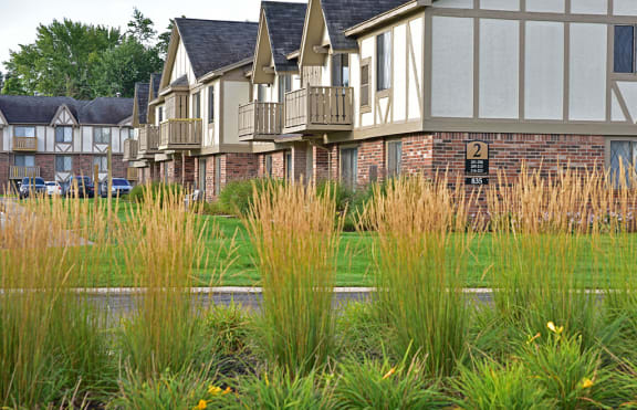 a row of houses with tall grass in front of them at Huntington Place Apartments, Essexville