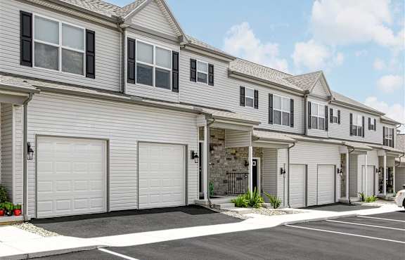 the front of a white house with two garage doors