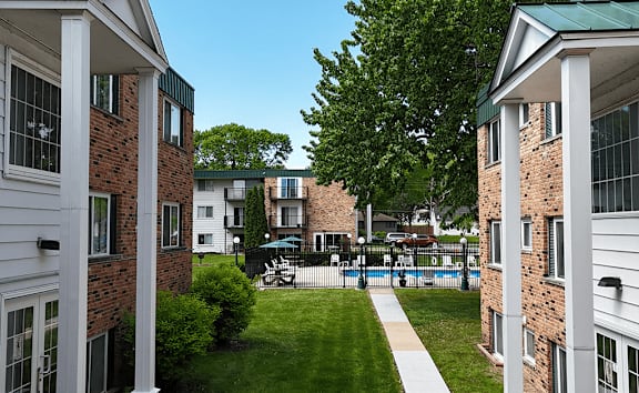 A view of a courtyard between two buildings with a white walkway.