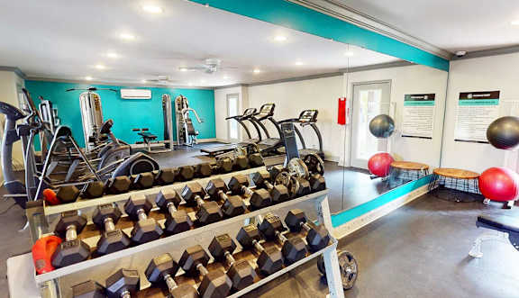 A gym with a variety of equipment including dumbbells and weight machines.