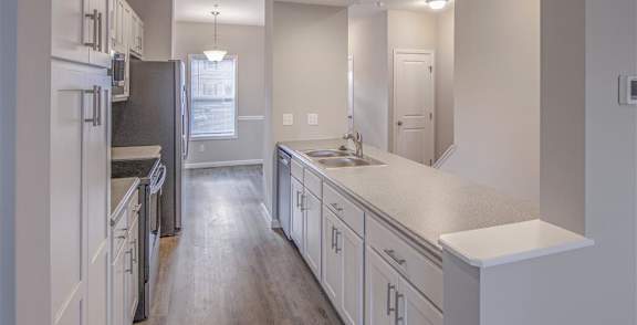 A room with a black fridge and wooden flooring.