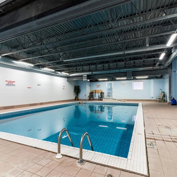a swimming pool in a large room with tile floors and a metal ceiling
