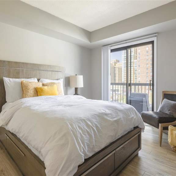A bedroom with a large bed and a chair by the window.