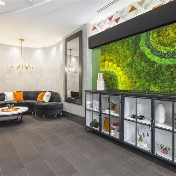 A living room with a grey sofa and a glass cabinet with vases on it.