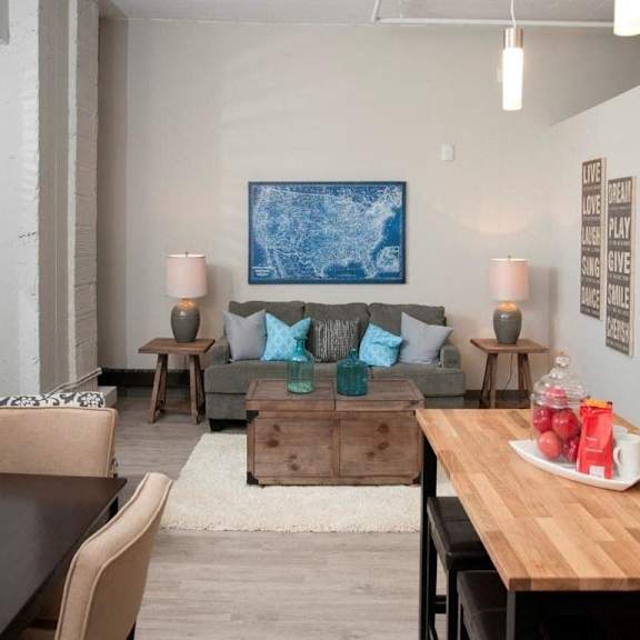 A modern living room with a grey couch, a wooden coffee table, and a painting on the wall.