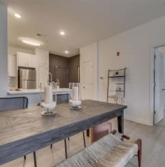 a long wooden table with candles on it and a kitchen in the background at Flats at West Broad Village in Glen Allen, Virginia 23060