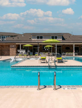 a swimming pool with chairs and umbrellas in front of a building