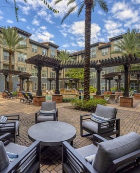 an outdoor patio with chairs and tables and buildings in the background