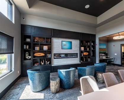 a living room with blue chairs and a television  at One Deerfield, Mason, Ohio