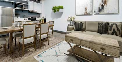a living area with a couch table and chairs and a kitchen in the background