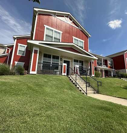 a row of red houses on a hill with green grass at Watermark at Steele Crossing, Fayetteville, AR