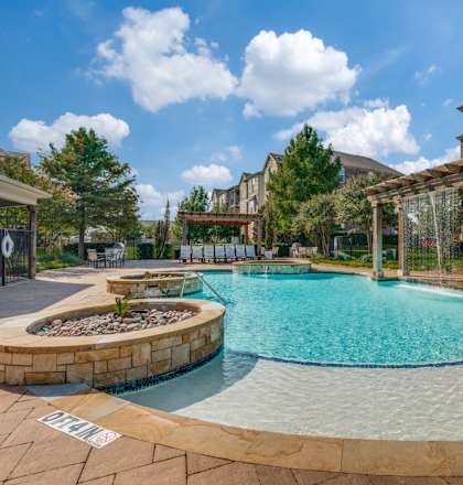 A pool surrounded by a stone wall with a white sign on the ground.