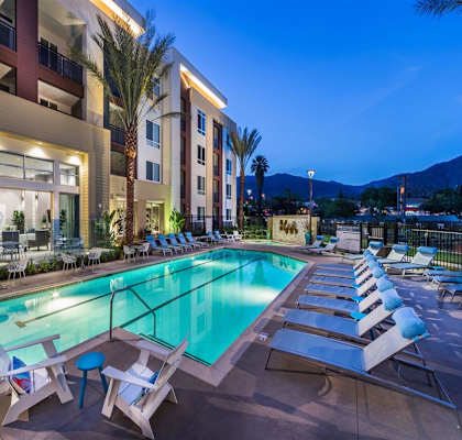 a swimming pool with chaise lounge chairs and a hotel in the background