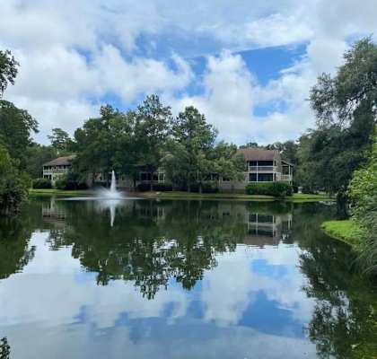 A serene lake surrounded by lush greenery and a building in the distance.