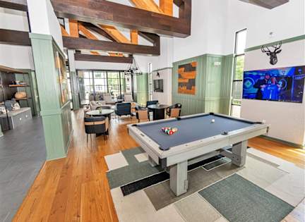 A pool table is in the middle of a room with wood floors and a high ceiling. at DAWSON PARK Apartments , BATON ROUGE, LA, 70809