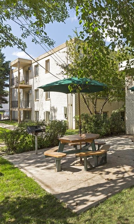 a patio with tables and umbrellas outside of a building at Hamline Terrace, Roseville, MN, 55113