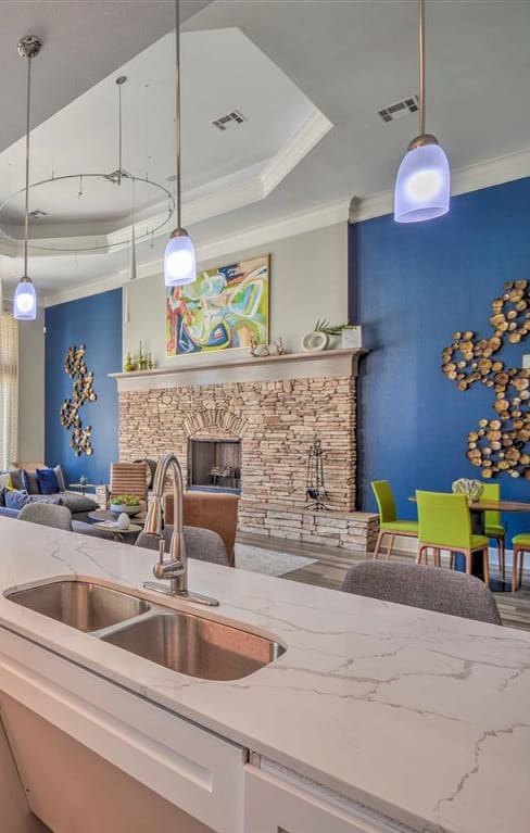 a kitchen with a sink and a living room with a fireplace at The Atlantic Mansfield, Mansfield, Texas