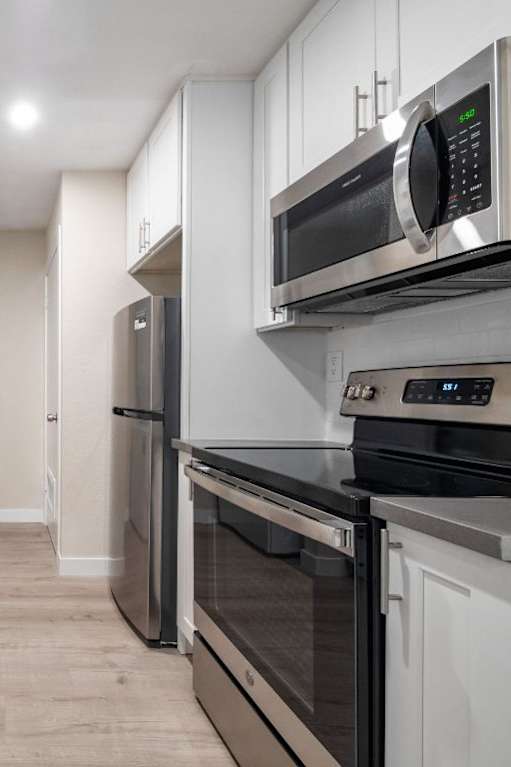 A modern kitchen with white cabinets and stainless steel appliances.